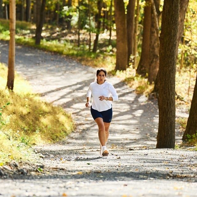 Löpare joggar på en grusad skogsstig i dagsljus